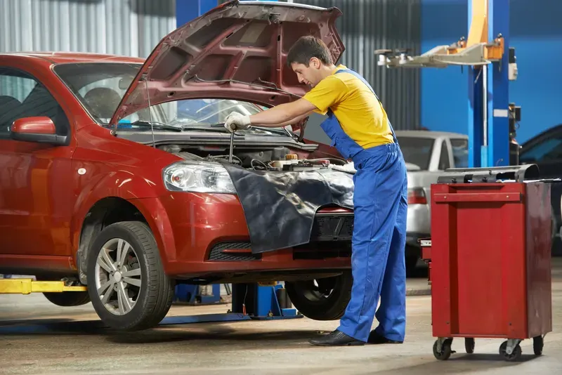 Mecanic auto lucrand la motor cu capota deschisa